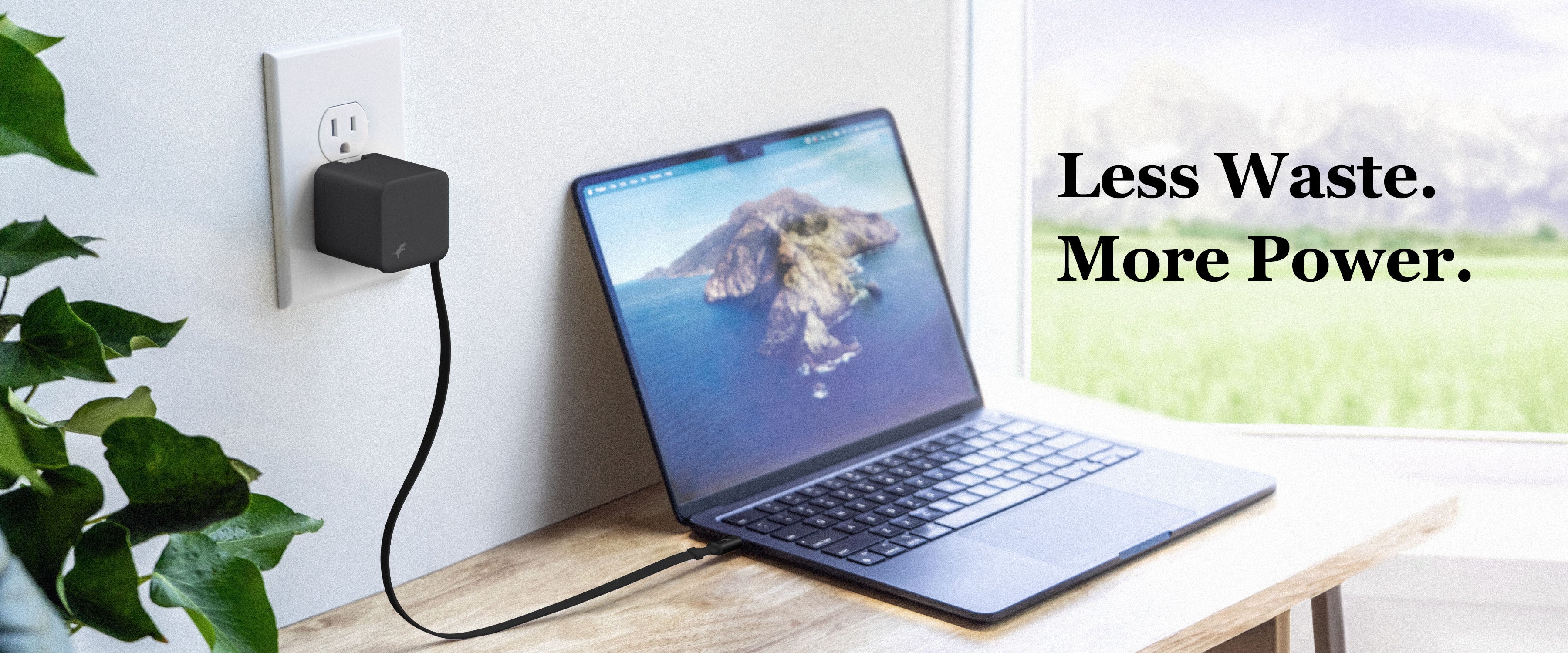 Black wall charger with USB-C cable connected to Macbook on desk near window and small plants to the left. Text overlay 