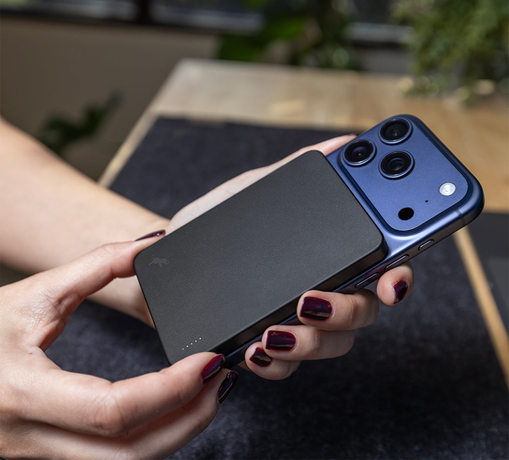 Hands attaching Champ Wireless 5K to blue iPhone 17 Pro with blurred background.