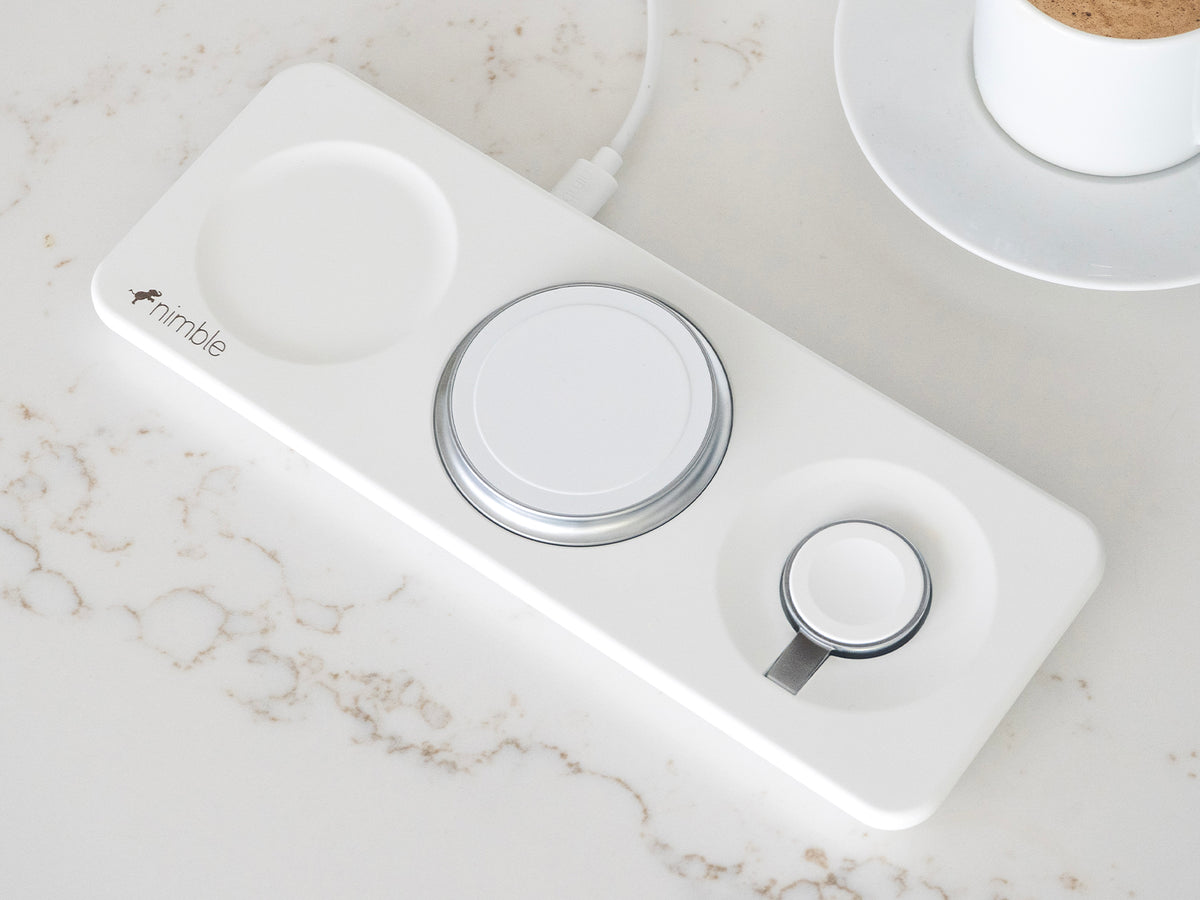 Podium 3-in-1 25W Wireless charging stand with dedicated spaces to charge iPhone, AirPods and Apple Watch devices on a marble surface.