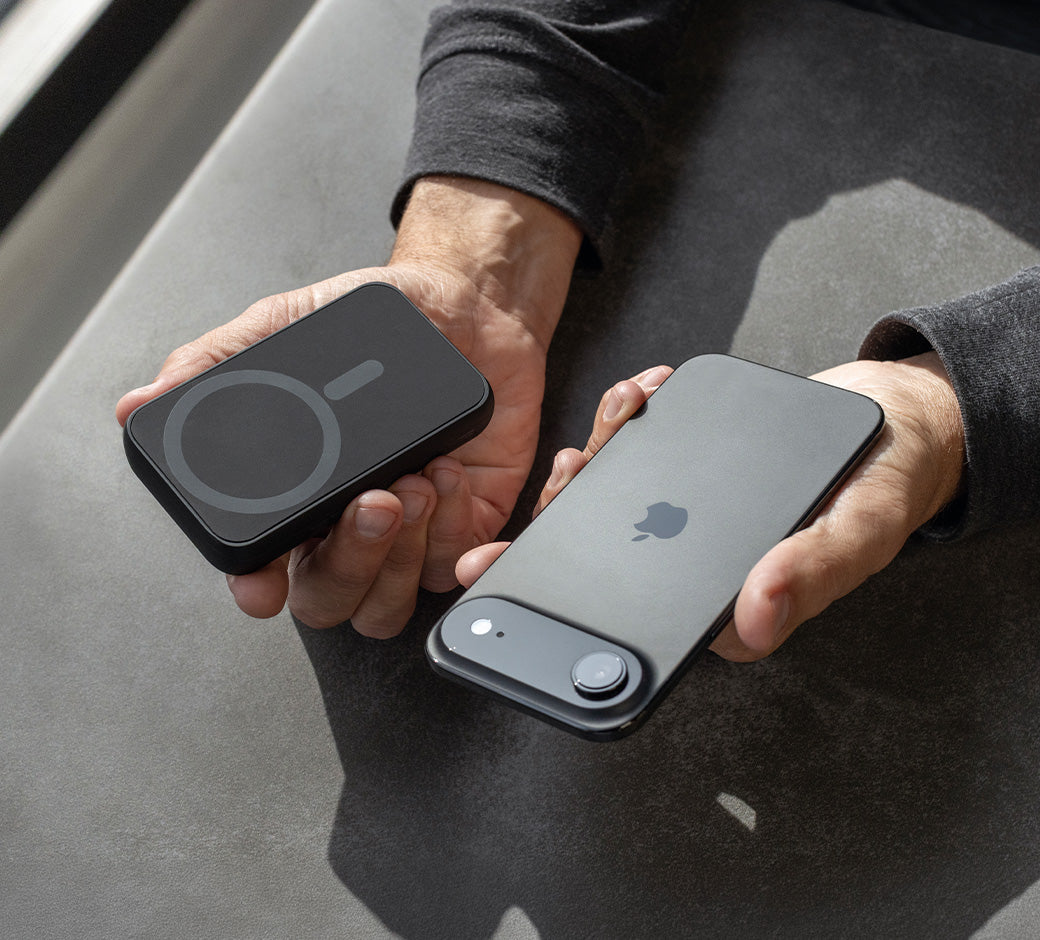 Person holding a black iPhone and Wally Pro Wireless on a gray surface.