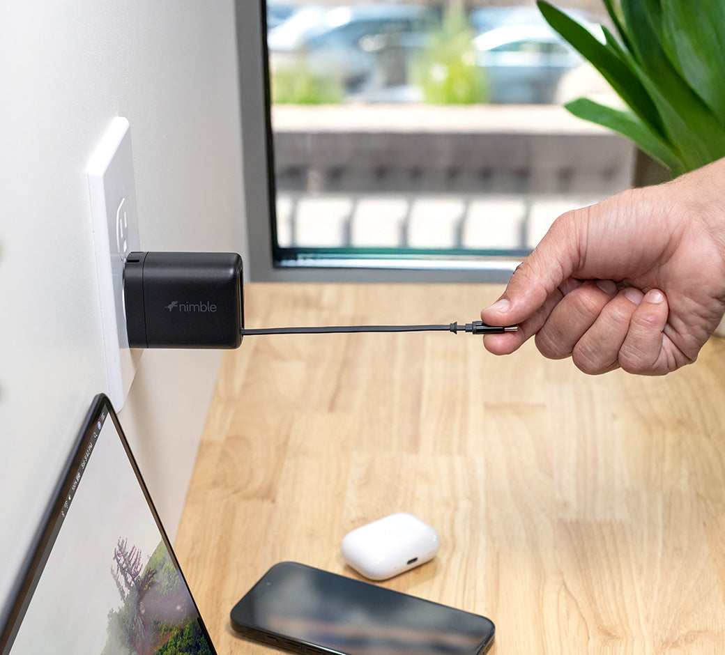 Person pulling built-in cable from Wally Stretch at a desk with a laptop and phone in the background.